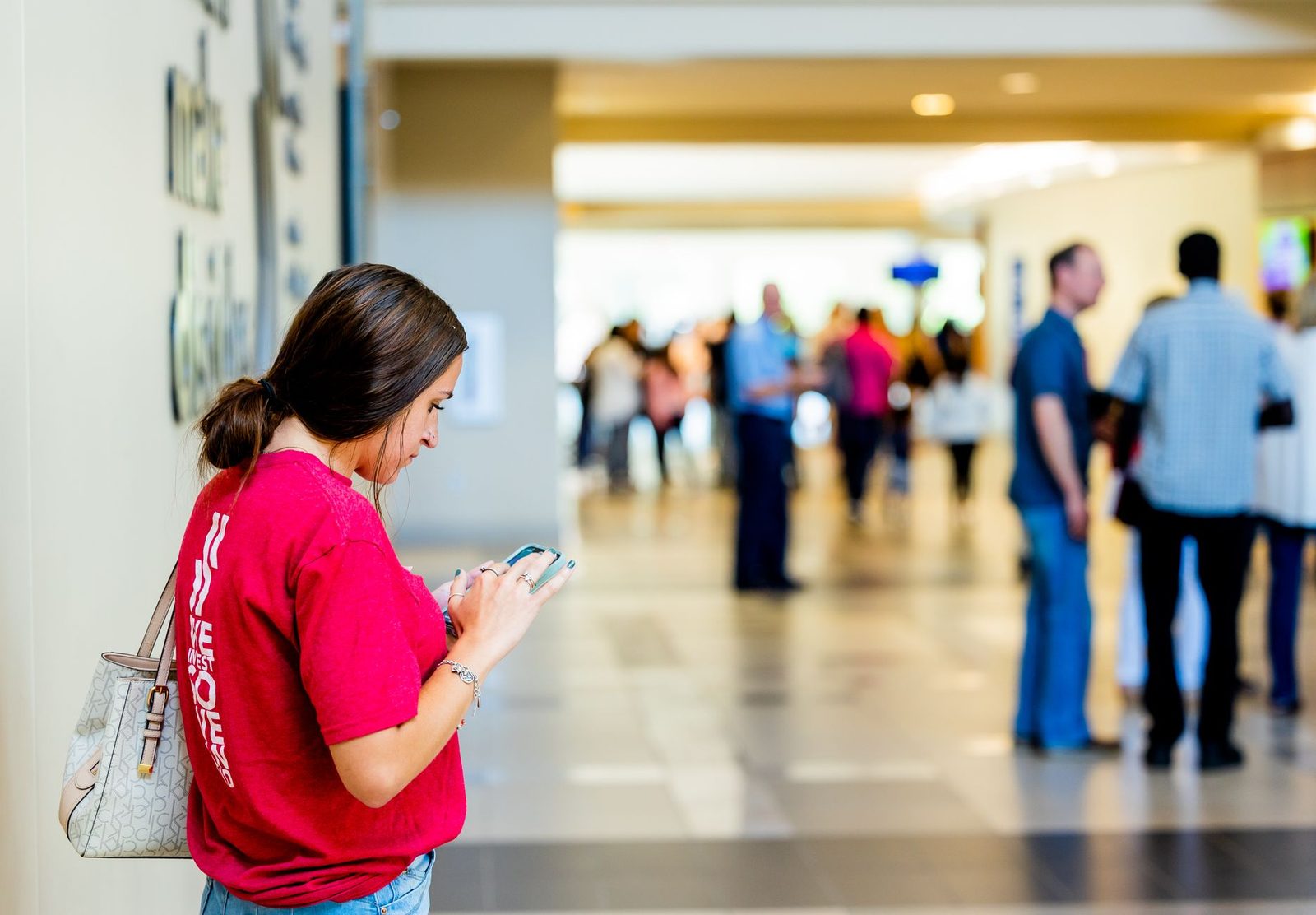 Administradora de centro de eventos revisando una ficha de espacios en un celular junto al plano del recinto